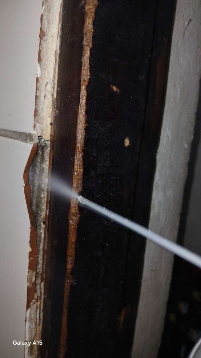 Inyección de termiticida en un marco de madera dañado por comején