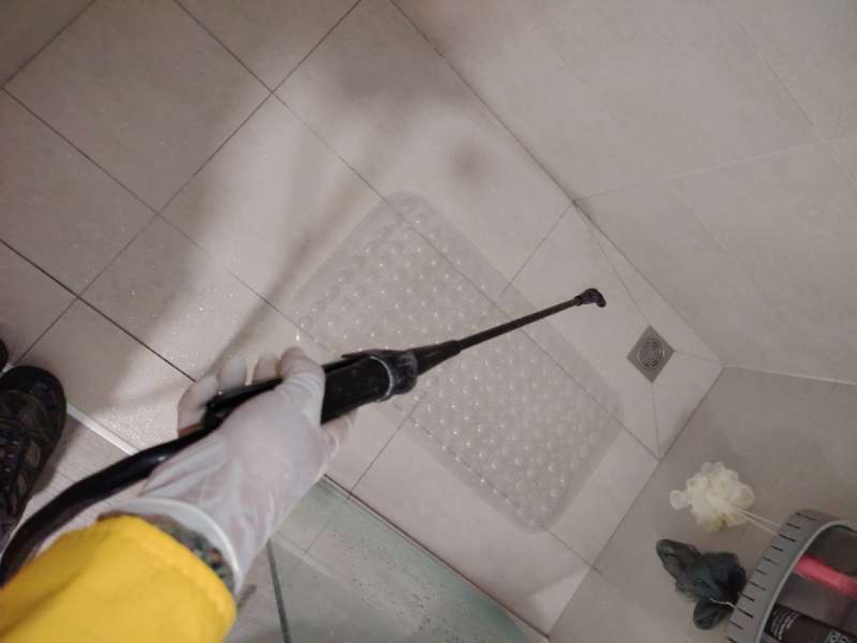 Aspersión de control de plagas en piso de baño junto al desagüe