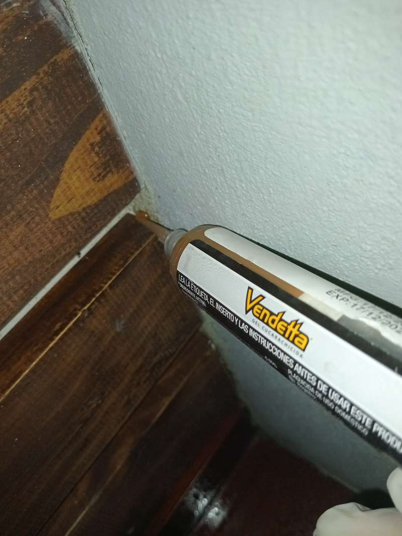 Aplicación de gel hormiguicida en la esquina de un mueble de madera