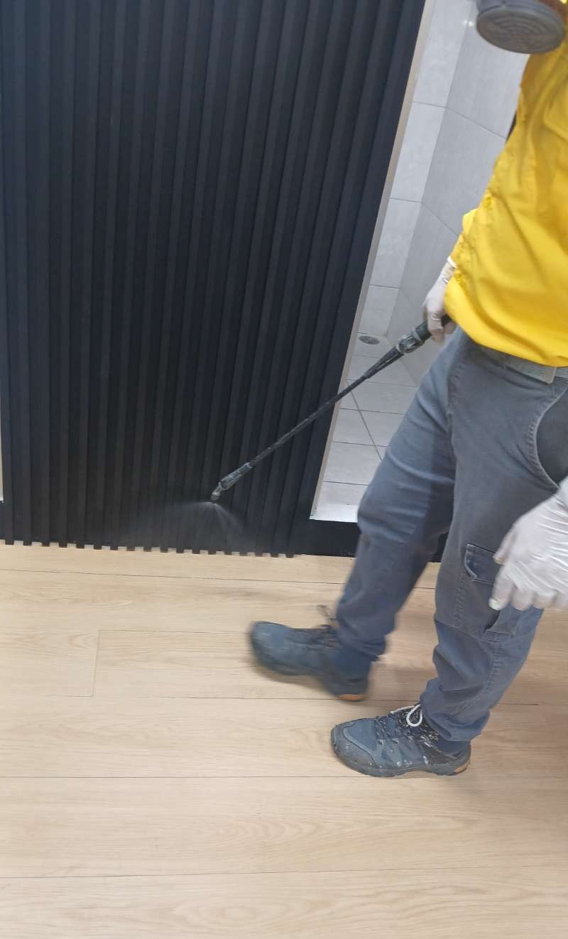 Técnico aplicando aspersión con lanza sobre piso de madera