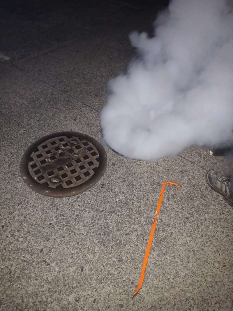 Niebla de tratamiento saliendo de una alcantarilla durante nebulización de drenajes
