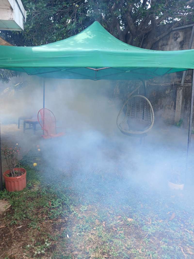 Nebulización contra zancudos en un patio residencial bajo un toldo verde